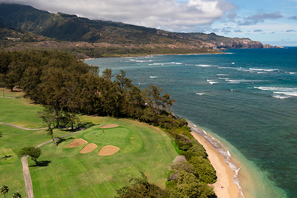 view of golf course against the ocean with mountain in distance