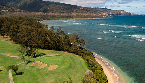 View of golf course against the ocean with mountain in distance
